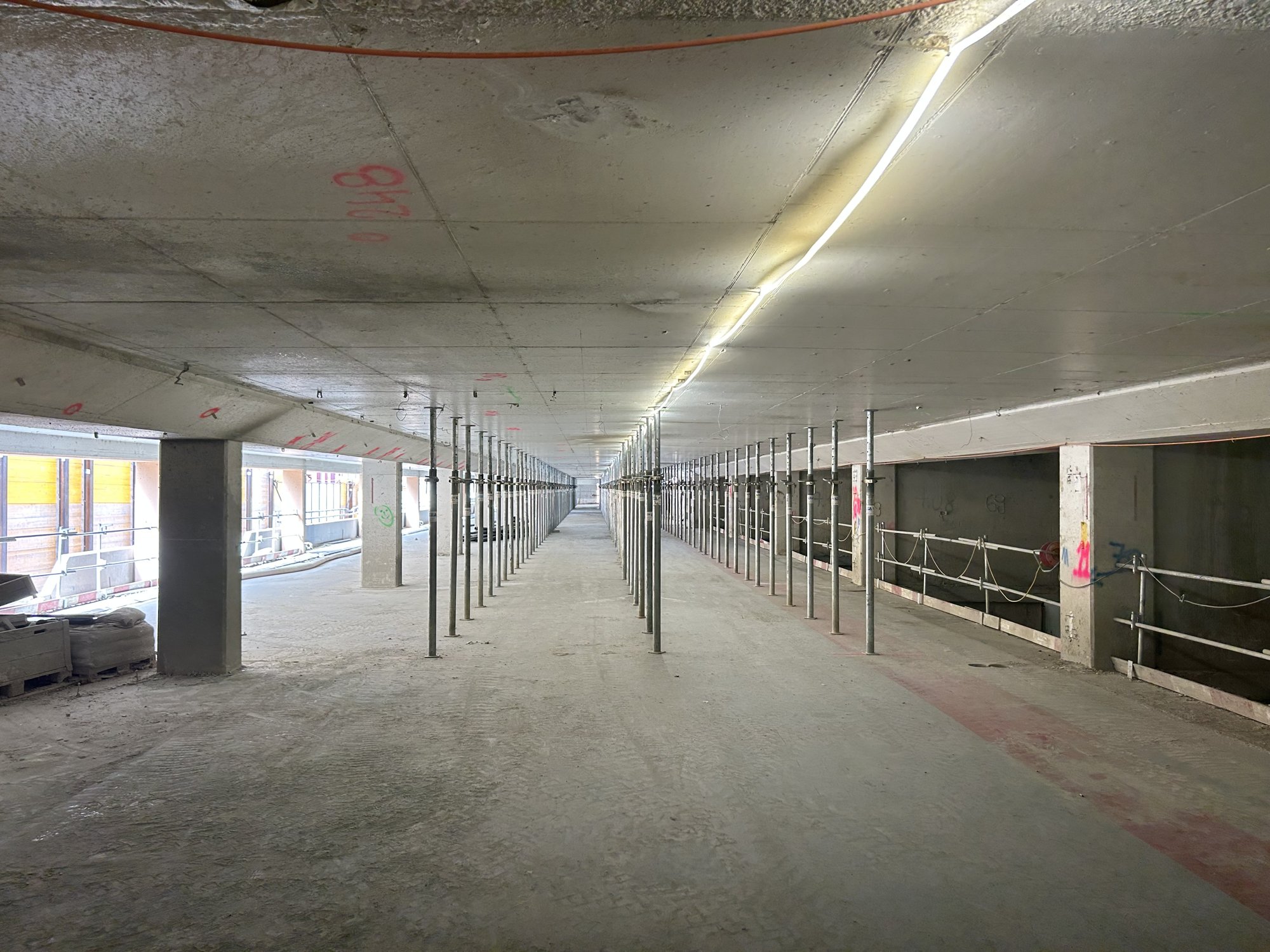 Long étage de parking en béton soutenu par des rangées d’étais métalliques.