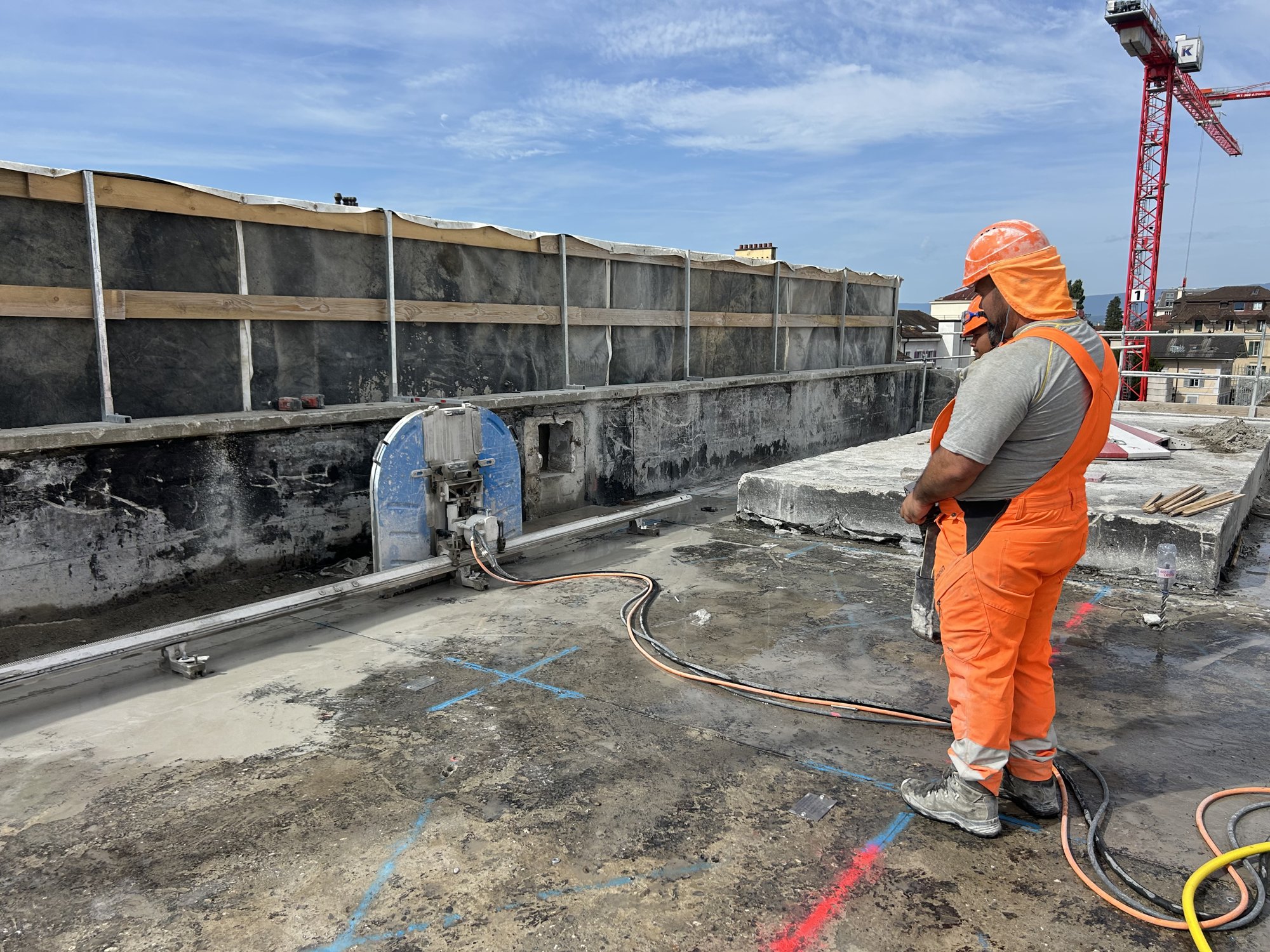 Ouvrier à côté d’une scie circulaire sur rail posée sur une dalle en béton.