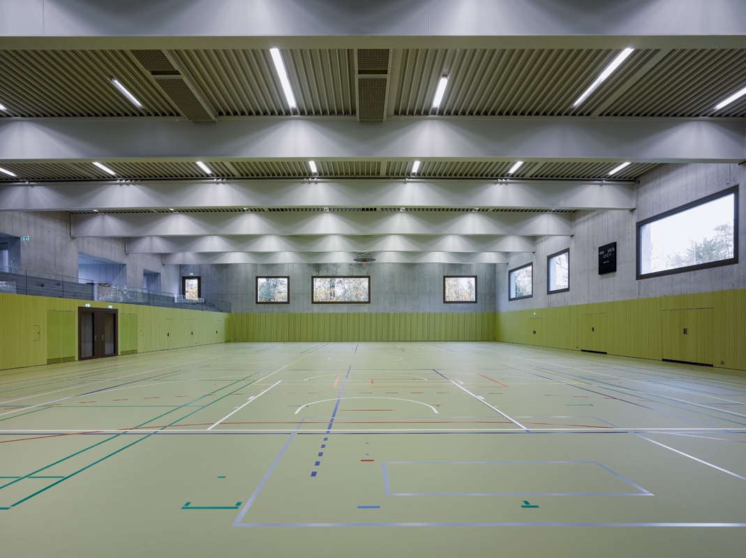 Im Hallenraum harmoniert der graue Sichtbeton mit den zurückhaltenden Farben der Holzlattung, die als Akustikverkleidung dient.