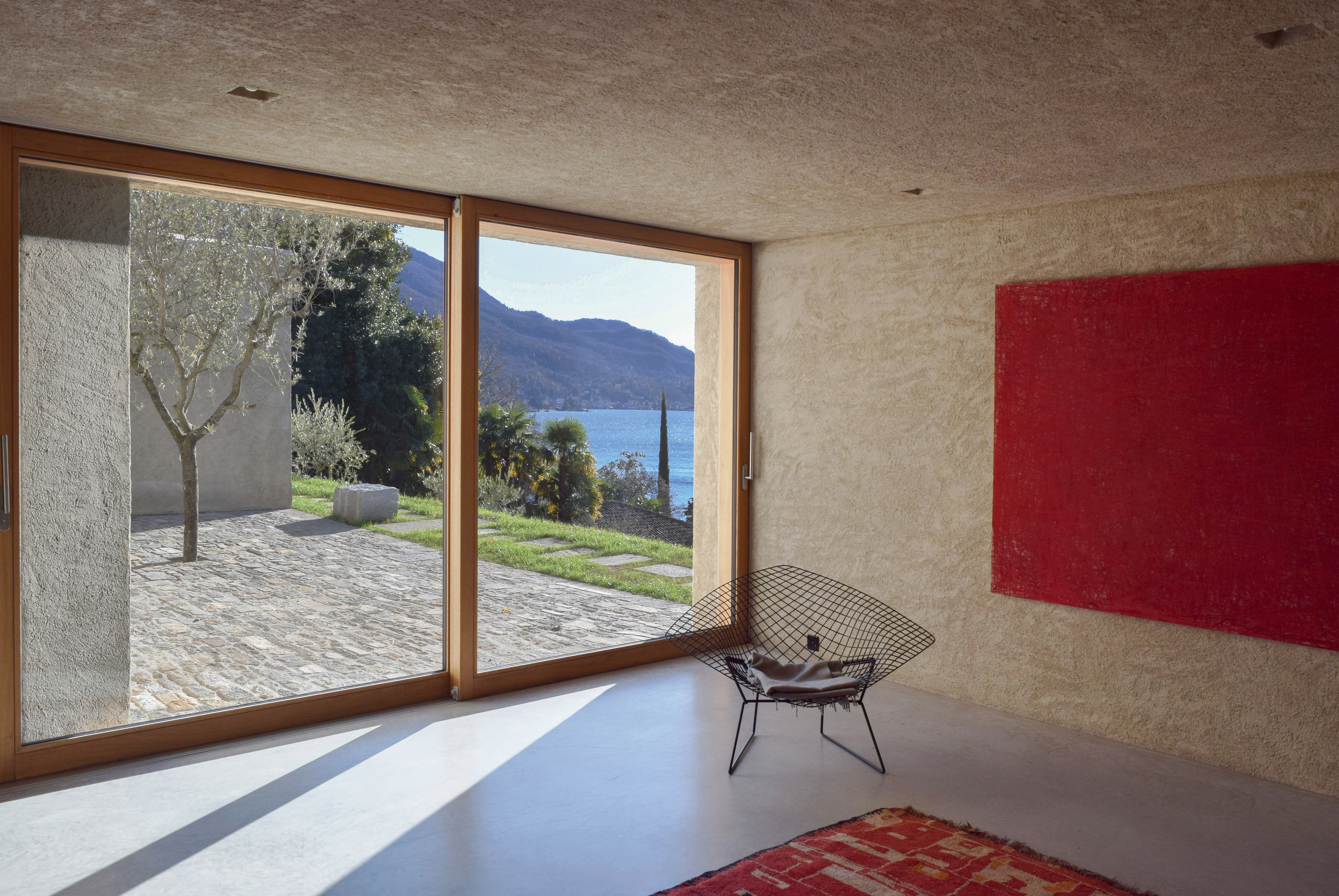 Mit dem Olivenbaum auf der Terrasse mit Blick über den See wird der Gedanke des ummauerten Olivenhains wieder aufgenommen.