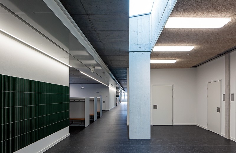 Erschliessungszone im 2. OG: Zeigt sich die Schulanlage von aussen kompakt und einheitlich, offenbart sich im Inneren ein komplexes Gefüge mit allerlei unterschiedlichen Räumen, Zonen und Nischen: So zweigen etwa kurze «Gassen» von der «Hauptstrasse» ab und führen auf kleine «Plätze» an Innenhöfen.