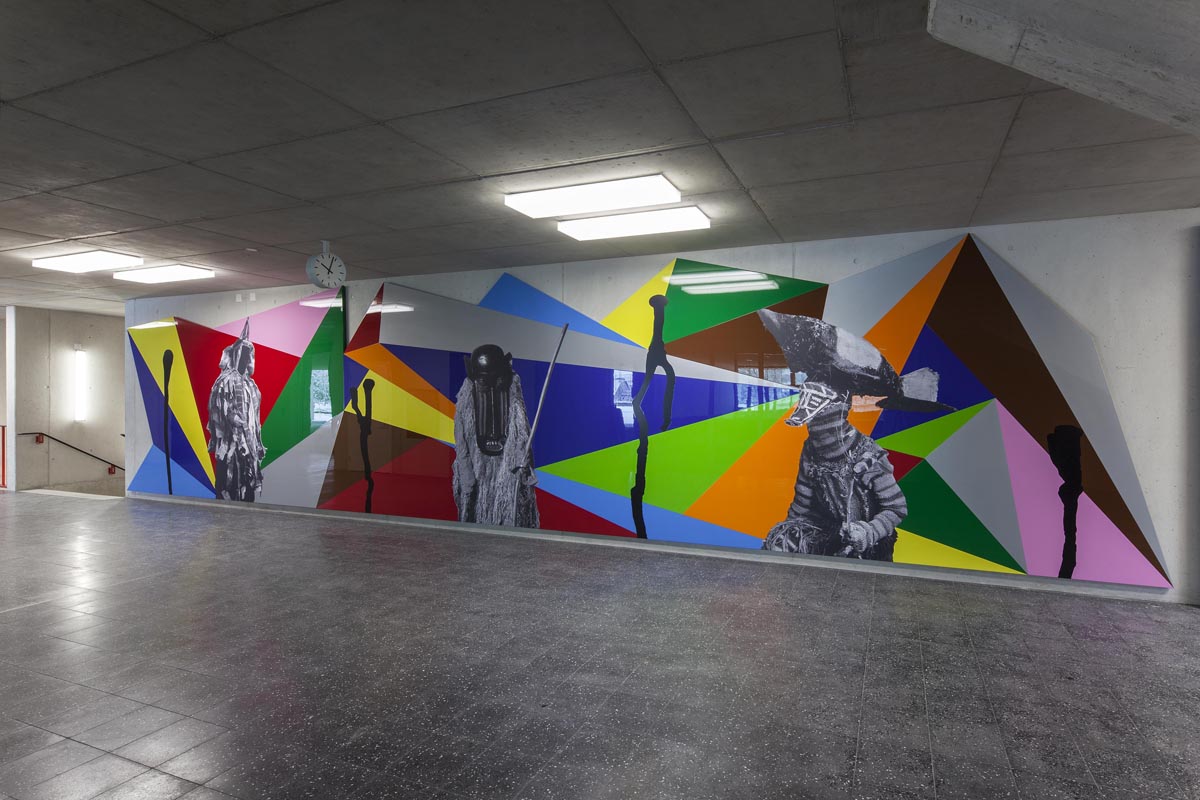 Kunst und Bau: Costa Vece, «Ratio vs. Emotio», 2016 Der Neubau wird durch eine mehrteilige künstlerische Arbeit bereichert. Das Eingangsfoyer des Schulhauses zeigt das monumentale Wandbild «Ratio vs. Emotio» des Zürcher Künstlers Costa Vece. Das rund 12,5 m lange und 2,8 m hohe auf Aluplatten aufgezogene Werk bezieht sich in seiner utopischen Geste auf die Zeit der Moderne und verbindet diese mit Themen und Praktiken der 60er- und 70er-Jahre.