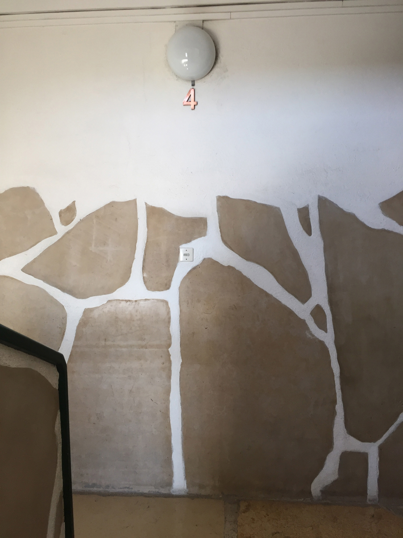 Eine Wand mit ausgesparten Sandsteinplatten im Treppenhaus.