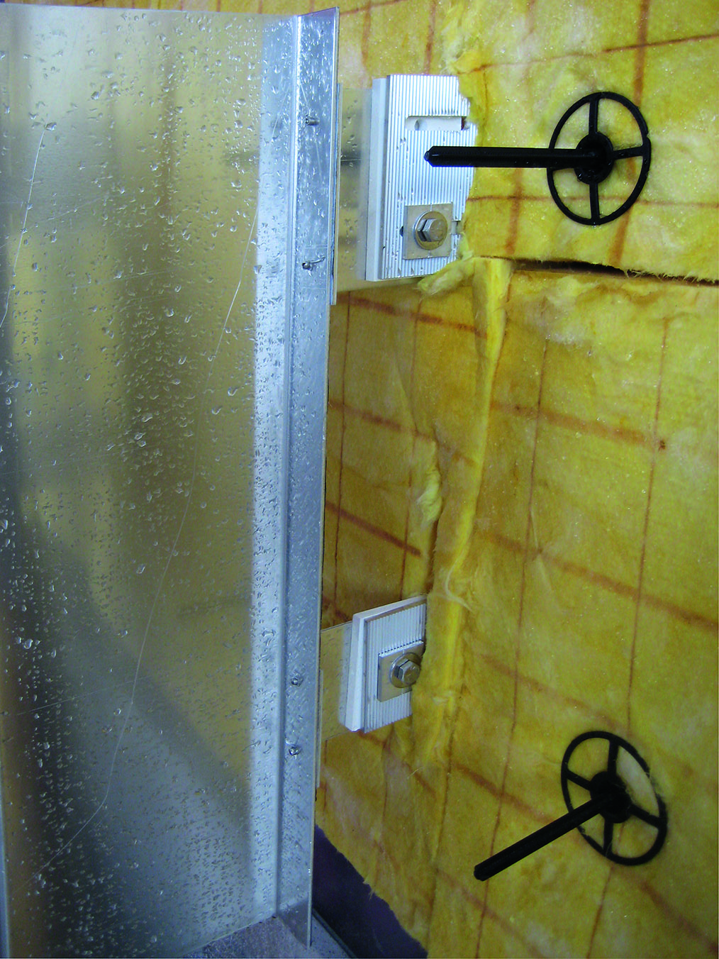 Dettaglio costruttivo con elementi di fissaggio isolati (con taglio termico) per la facciata ventilata di un edificio in standard Minergie-P-ECO