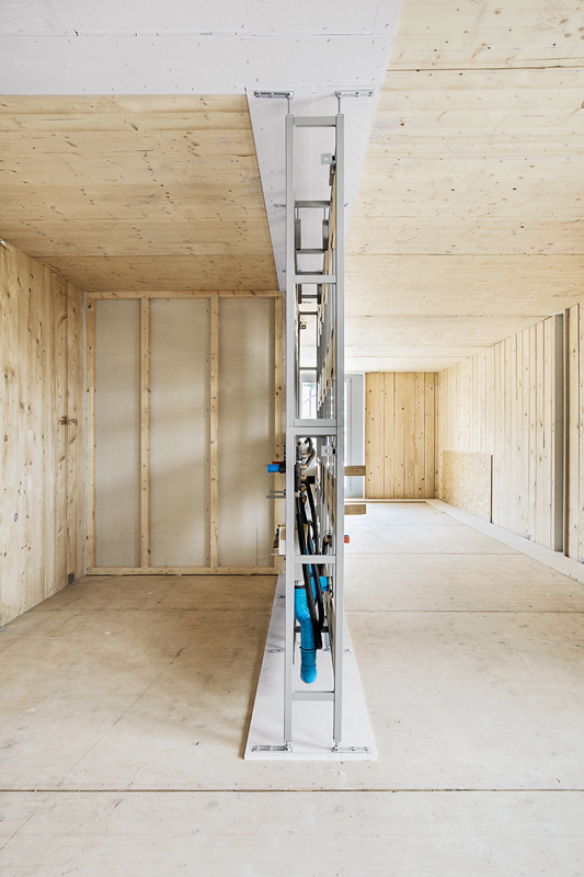 Wohnhaus Badenerstrasse, Zürich (Baujahr 2010): Die Installationen in den Wohnungen liegen in Vorwandelementen – hier die Installationswand im Rohbauzustand. Die horizontale Elektroverkabelung ist in sichtbaren Bodenkanälen verlegt (rechts an der Wand).