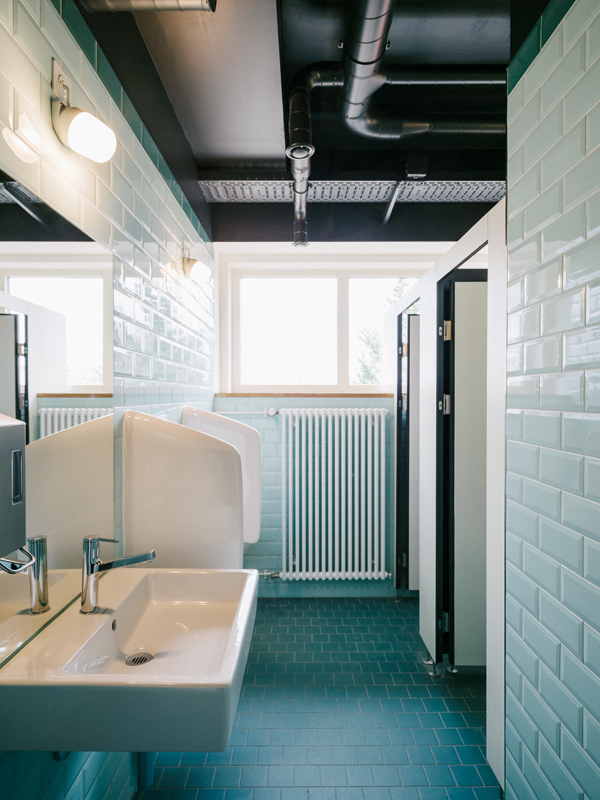 Durch den Verzicht auf eine abgehängte Decke konnten die grossen Fenster in den WCs erhalten werden. Die facettierte Keramik erinnert an die 1930er-Jahre.