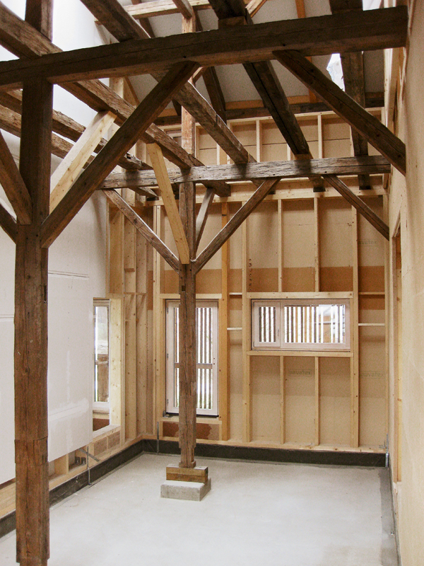 Ein Innenraum der wieder aufgebauten Torfremise in Schechen mit der alten Tragstruktur aus Holz und neuen Wänden.