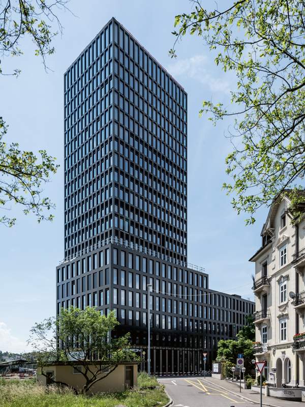 Die Pfosten und Riegel der Fassade des Grosspeter Towers lösen sich mit steigender Gebäudehöhe zugunsten grösserer Fassadenöffnungen auf. Das Tragwerk hinter der Fassade und die Solarmodule in den Fassadenpaneelen entsprechen dieser abgestuften Abmessung. Das ergibt trotz techni­sierter Fassadenelemente ein stimmiges Gesamtbild.