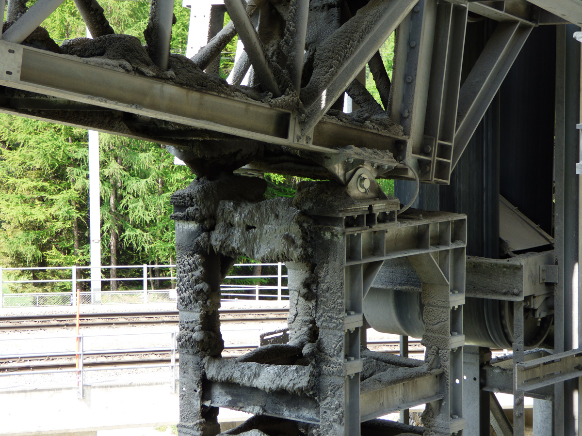 Gesteinsmehl und Schlamm unterhalb eines Förderbands.
