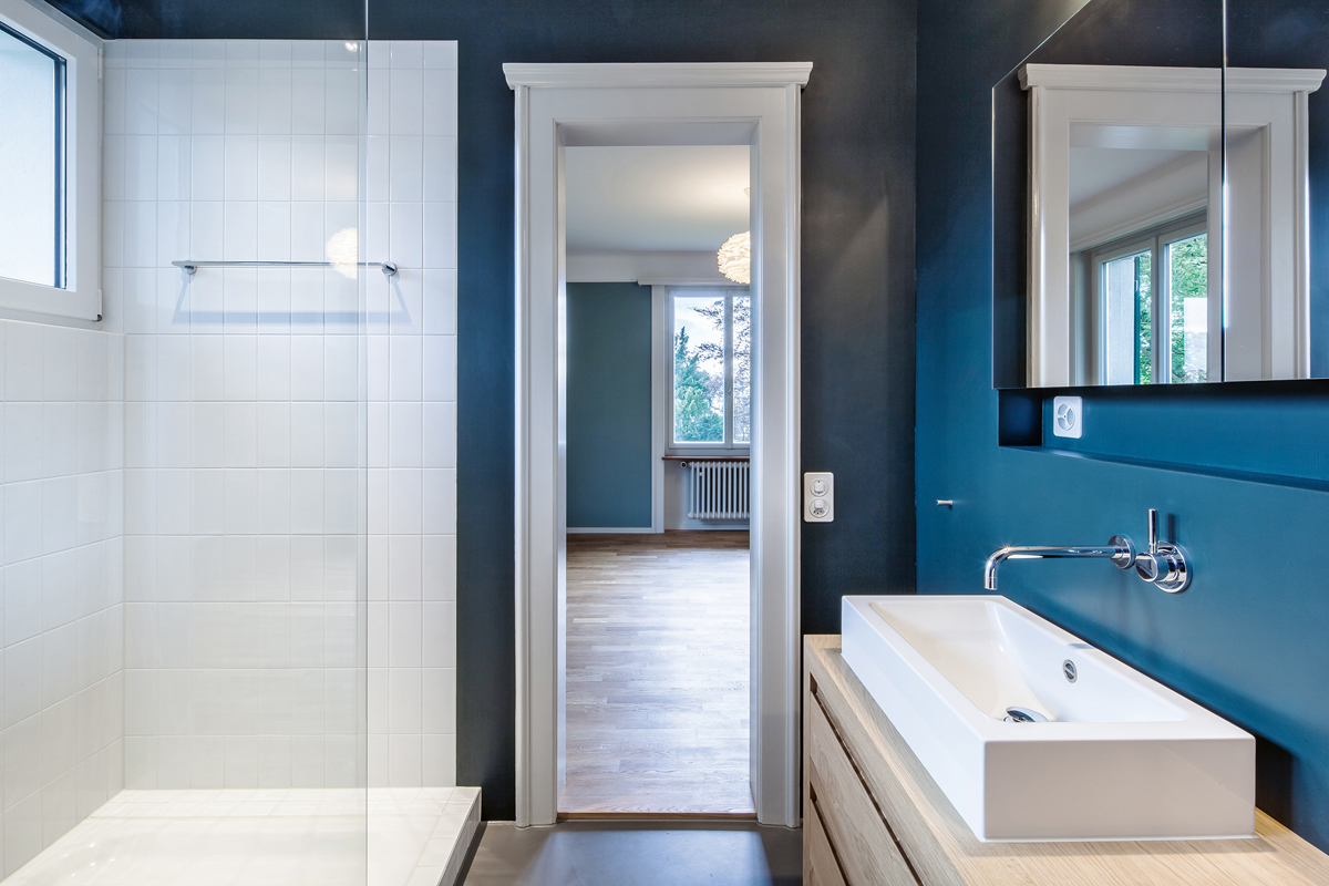 Durch das dunkle Waldgrün der Wände im Bad erhalten die weissen Bauteile eine betonte Körperlichkeit.