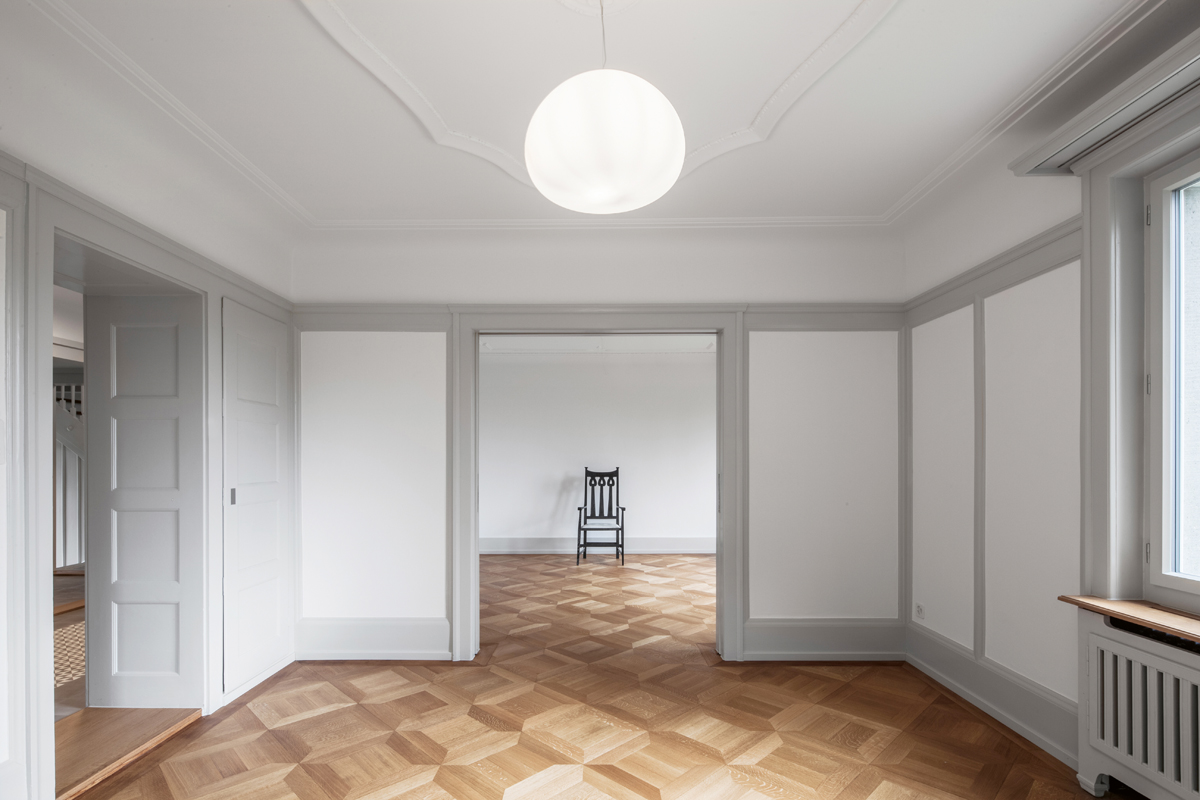 Im Wohn-, Ess- und in den Schlafzimmern wurde das Vorhandene erhalten und nur sanft saniert. Die farblich abgesetzten Holzeinbauten wie Türen und Schränke strukturieren die hellen Räume.