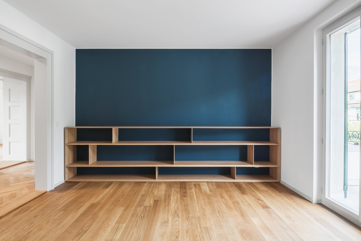 Die frühere Küche im Obergeschoss wurde zur Treppe und zum Wohnungsflur hin aufgebrochen. Mit dem halbhohen Bücherregal entsteht eine Bibliotheksatmosphäre.