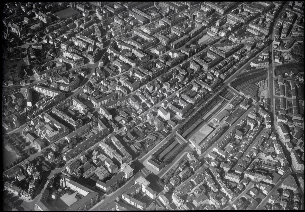 Blick aus dem Flugzeug auf Alt-Wiedikon aus dem Jahr 1948; in der Mitte unten sind der Bahnhof und der Seebahneinschnitt sichtbar. Auf dem nordöstlich gelegenen Areal ist der letzte Teil der ursprünglichen Dorfsiedlung sichtbar; am südwestlichen Ende markiert das Bauernhaus die aktuelle TEC21-Adresse.