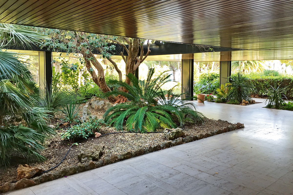 Das schattige Vordach der Résidence Athéna mit tropischer Bepflanzung dient als Zugang zu dem ehemaligen Hotel.