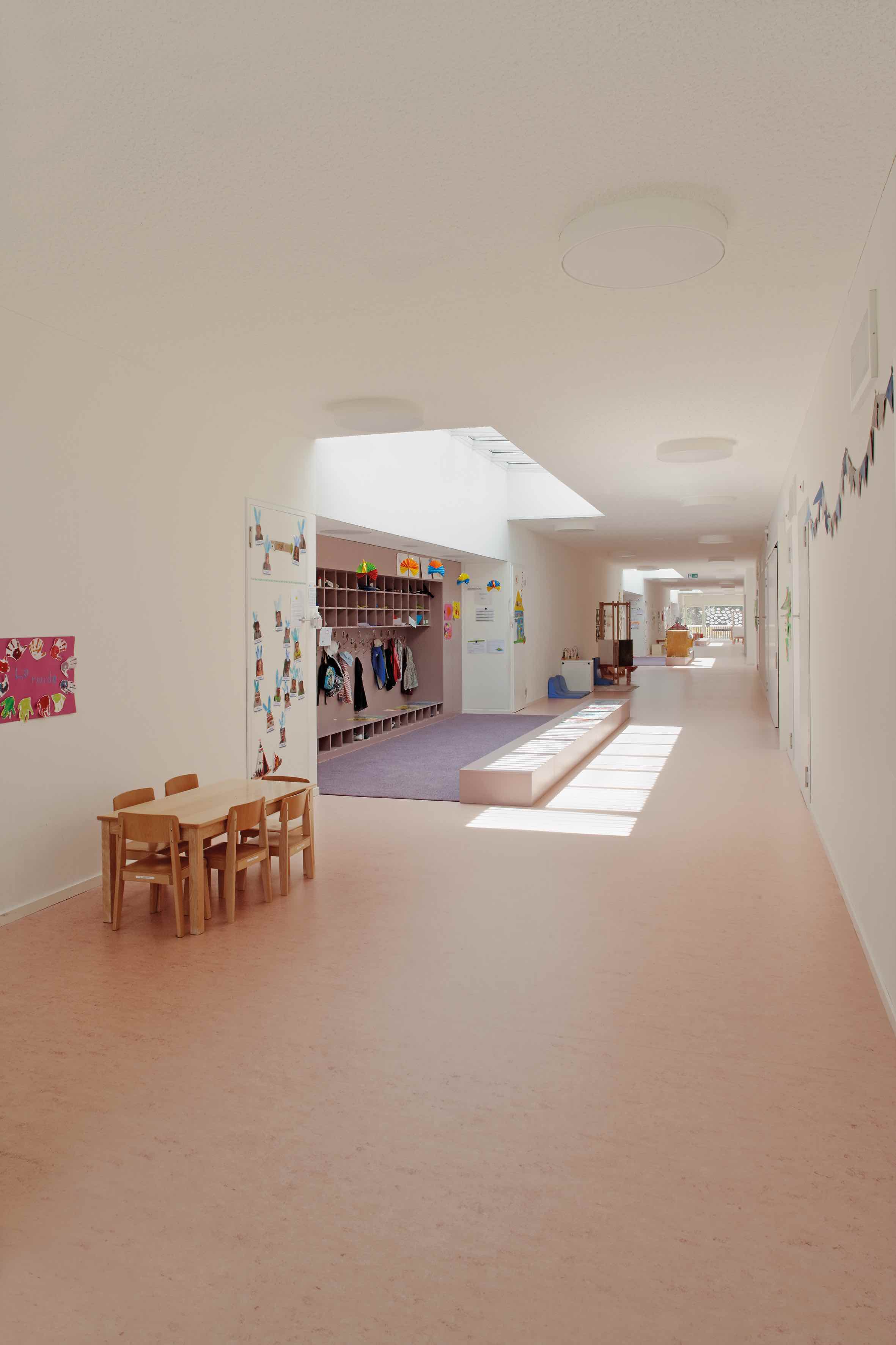 La terrazza-camminamento è protetta dal sole da tende bianche. Il corridoio interno animato dalle attività dei bambini.