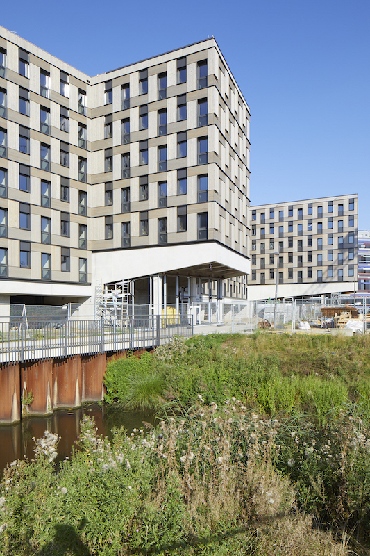 Das Studierendenwohnheim «Woodie» ist ein Holzmodulbau mit sechs Geschossen und 371 Studentenwohnungen. Es ist das derzeit grösste Holzhaus Hamburgs. In den 20 m² grossen Holzmodulen sind Dusche, Waschbecken, Bett, Schreibtisch, Tisch, Schränke und eine Küchenzeile integriert.