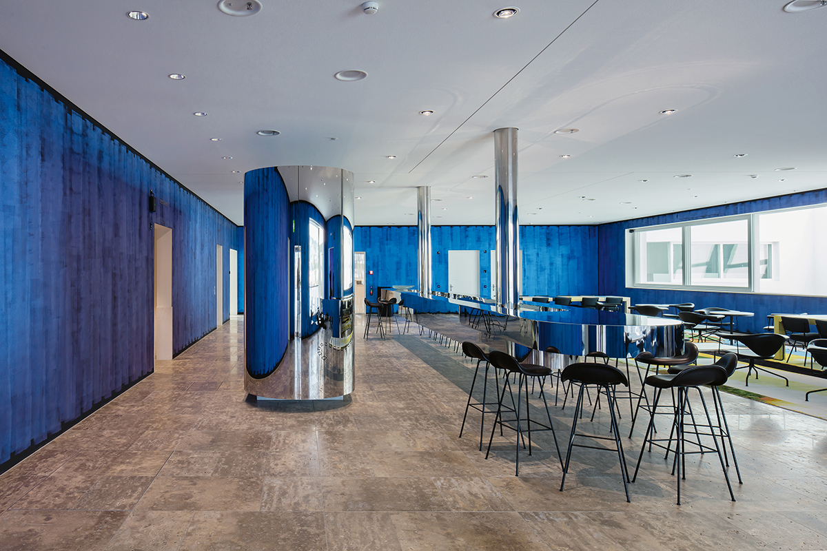 Der Gästeempfang im fünften Obergeschoss besticht durch eine abgehängte Edelstahlbar und die farbigen Wände.