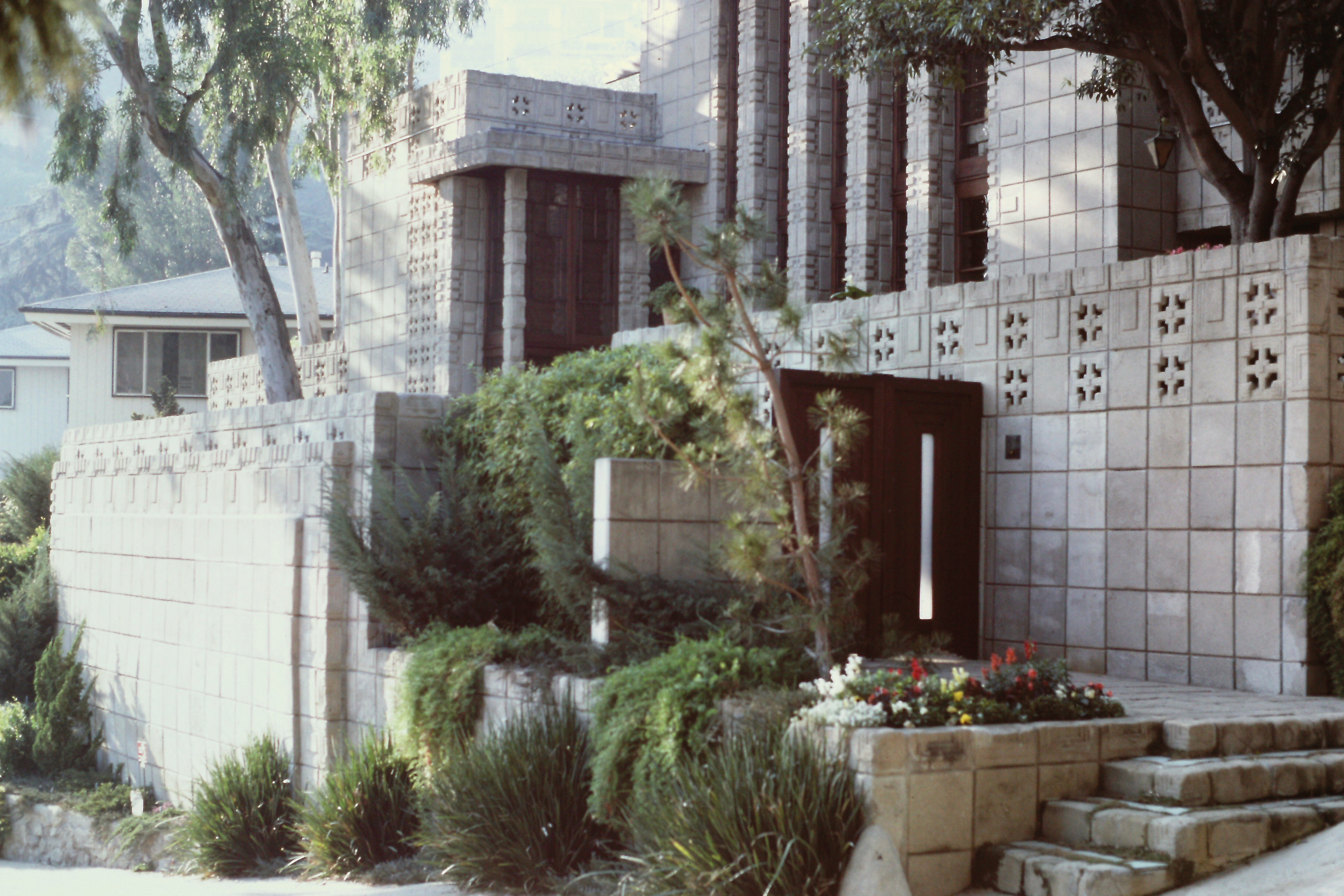 Carnet Amérique Dimanche 1er février 1987 « Redescendu jusqu’à Hollywood Boulevard, parcouru jusqu’à son extrémité O, monté sa branche O après Laurel Canyon Boulevard pour voir – toujours de l’extérieur – la Storer House, FLW, 1923 ; ici, la façade panoramique se trouve côté rue : il y a un corps de bâtiment central toujours wrightien avec poteaux et avant-toit, plus des ailes et des terrassements Le tout, revêtu des habituels carreaux de ciment estampé. L’accrochage au terrain e