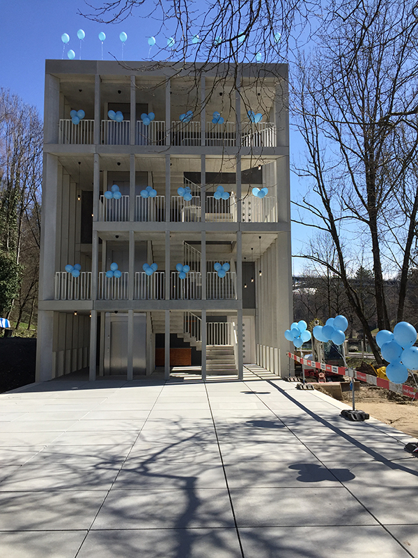 Zum Platz hin zeigt sich das geradezu theatralische Treppenhaus des Neubaus als Membran zwischen Innen und Aussen.