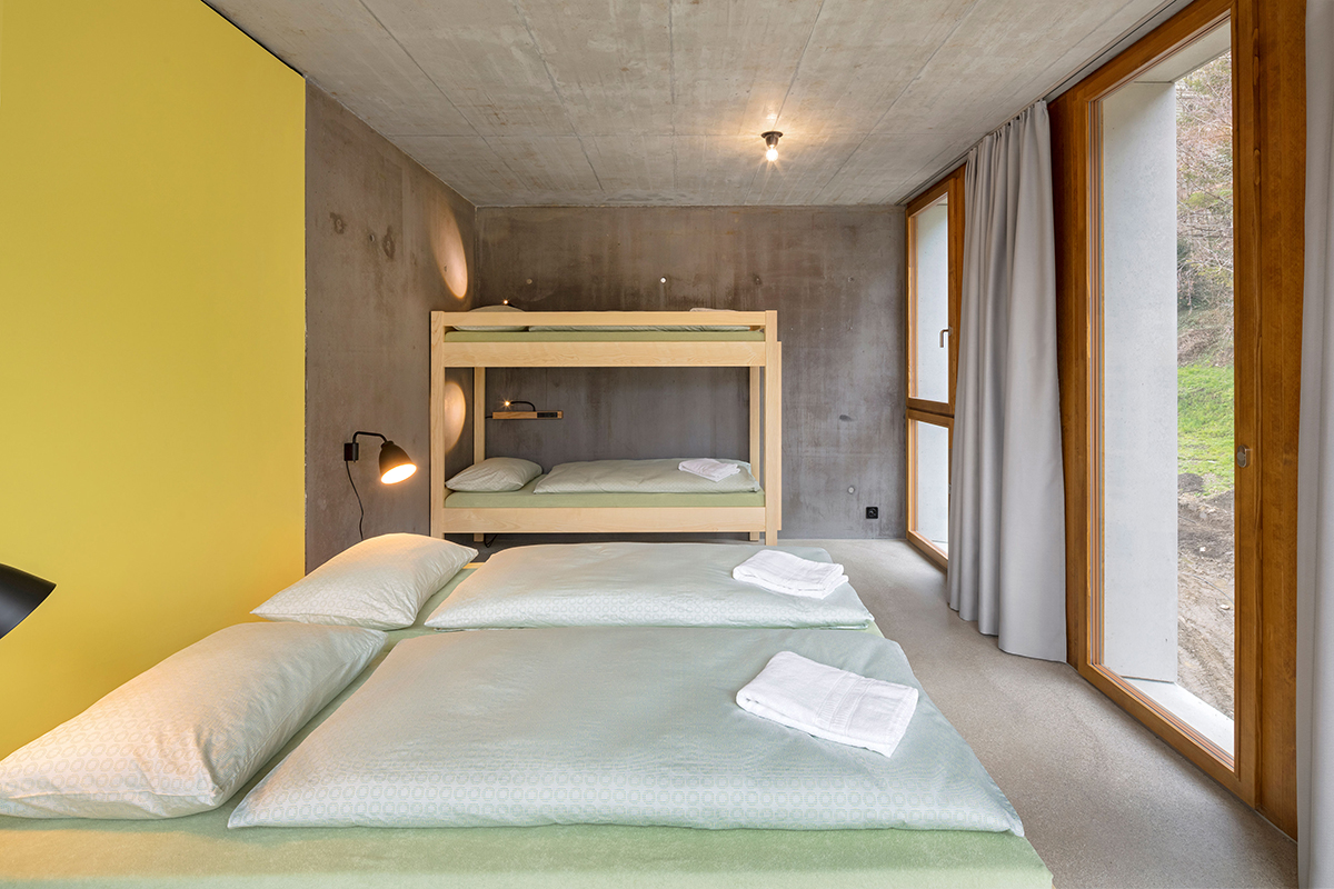 Familienzimmer im Neubau. Schlichte und funktionale Ausstattung. Im gelben Einbau befinden sich Bad und Stauraum.