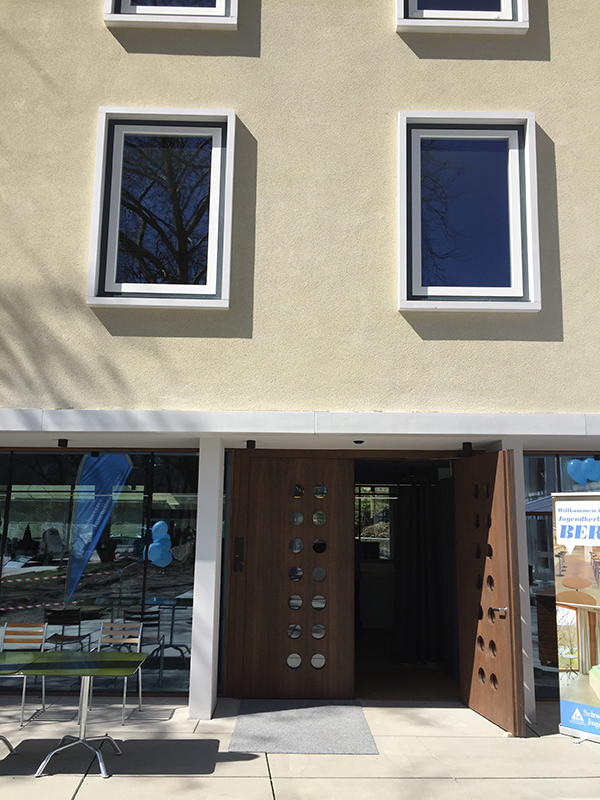 Zugang zum Empfang und der Bar im Altbau. Die expressiven Fensterrahmen wurden in ihren ursprünglichen Zustand versetzt und dienten als Vorlage zur Gestaltung der Fenster im Neubau.