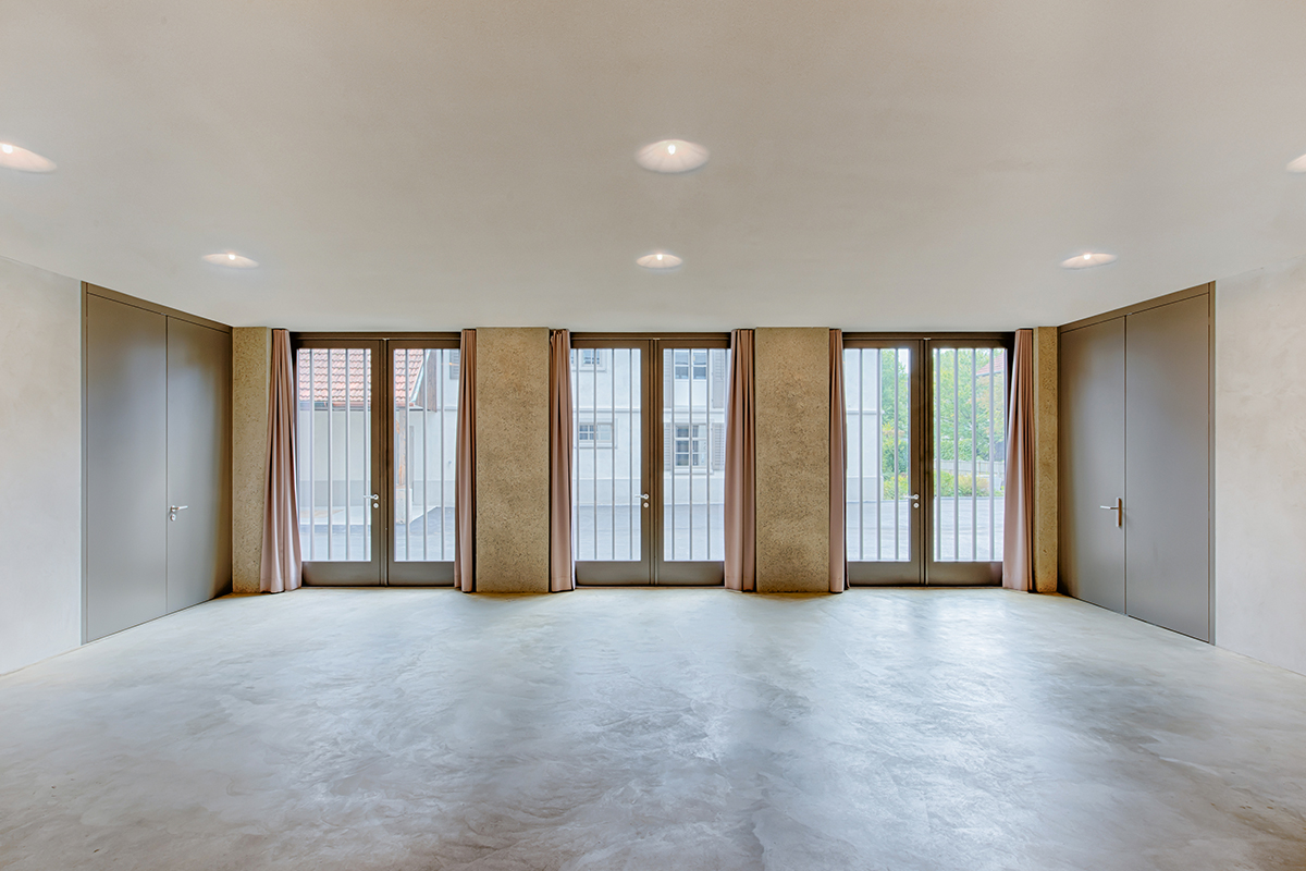 Das Forum bildet das Herzstück des Baus. Im Innern ist die Wirkung der Oberflächen in der Anwendung erfahrbar. An der tragenden Struktur ist der Waschputz als Volumen bis nach aussen gezogen.