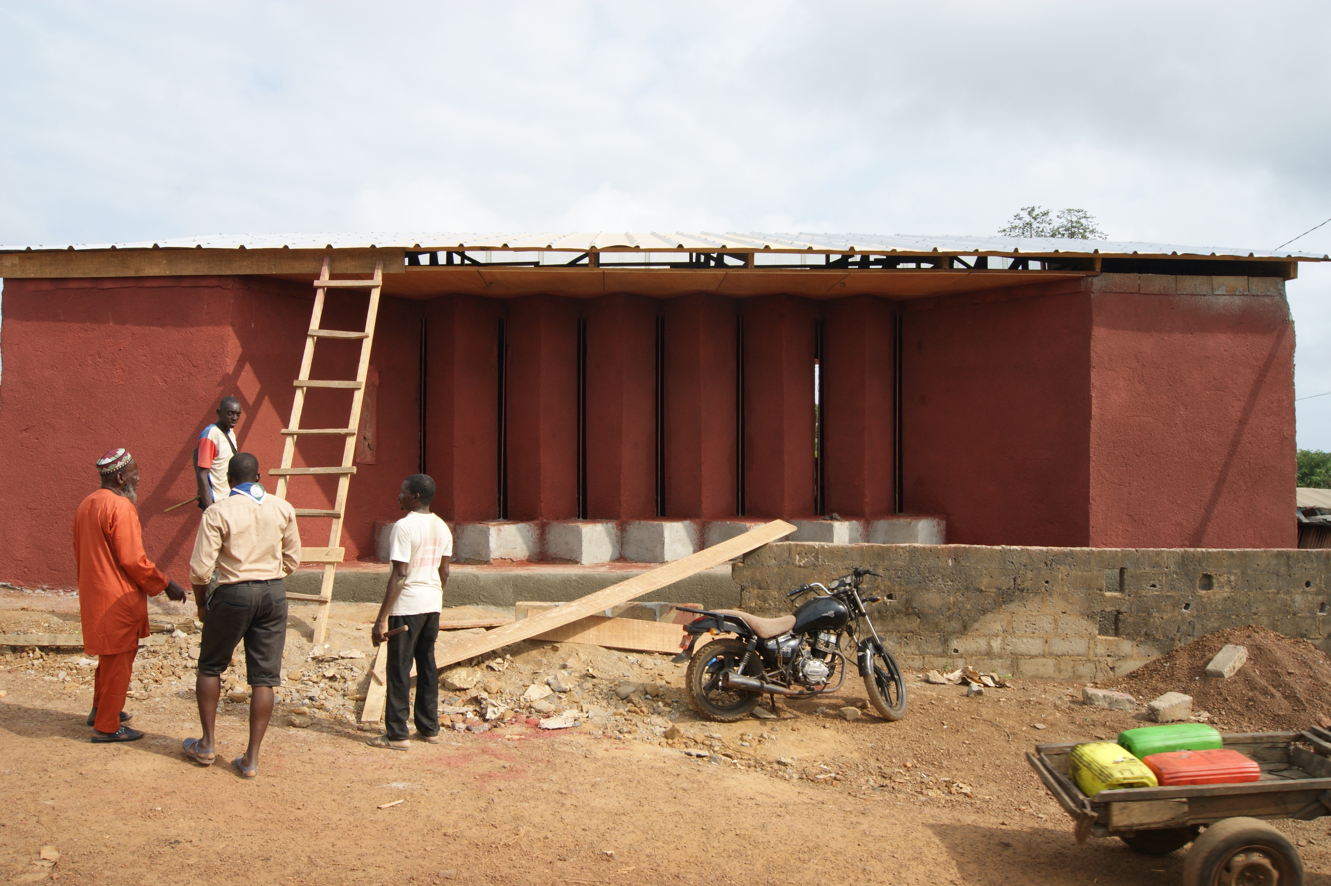 Façade côté rue, réunion de chantier entre Ladji, son père et des ouvriers.