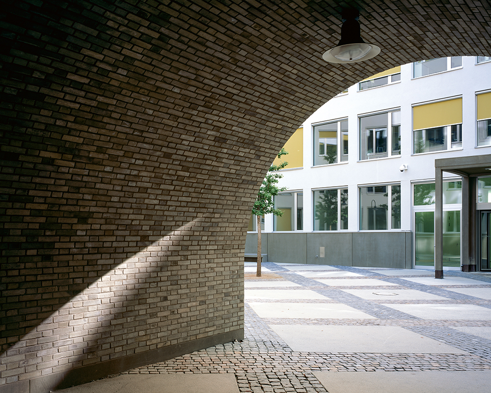 Beim Durchgang zum Innenhof trifft der opulent eingesetzte Backstein der Strassenfassade auf die schlichte weisse Putzfassade des Hofs.