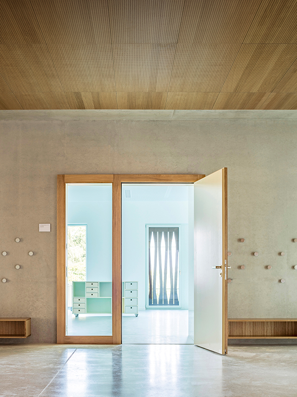 Blick in einen Kindergarten. Die Erschliessungsflächen sind jeweils in der Materialfarbe belassen, die Klassen monochrom farbig mit korrespondierender Möblierung gestaltet.