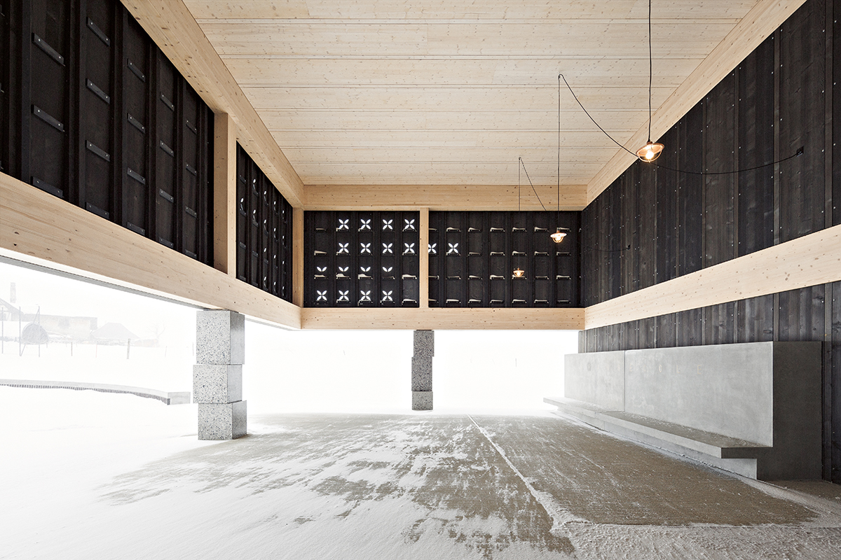 Der überdachte Pausenbereich vor dem Haupteingang. Gestapelte, versetzte Steinquader inszenieren das Moment des Tragens.