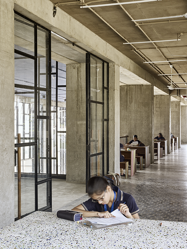 Die mit Bambusgittern beschatteten Veranden bieten ein angenehmes Klima und werden gern als Arbeitsort genutzt. Tischplatte aus Terrazzo mit farbigen Glassplittern aus Altglas gewonnen.