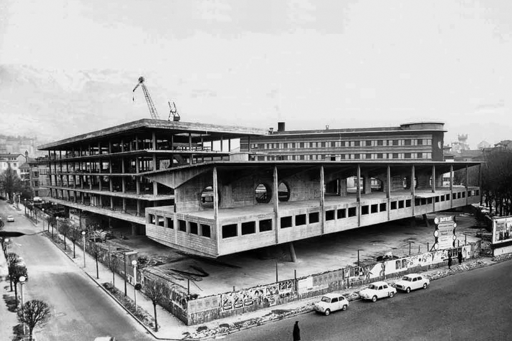 Die Baukörper von Assessorati und Giunta im Rohbau: Das Stahlbetonskelett der Giunta als Doppel-T-Träger, dessen kastenförmiger unterer Flansch das 1. OG ist. Im ausgeführten Bau gibt es in der Fassade nur noch eine Reihe von Pendelstützen im 2. OG (Foto: Sergio Musmeci, Privatdruck, CESICA Pordeno