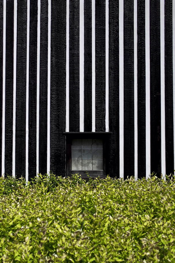 Normalerweise sind die Fassadenbretter kürzer als zwei Meter. Die Verwerfungen, die an den Kanten durch das Abflammen entstehen, sind in diesem Fall geringfügig. Bei den acht Meter langen Brettern des Thermalbads Lamune Onsen waren sie hingegen problemati