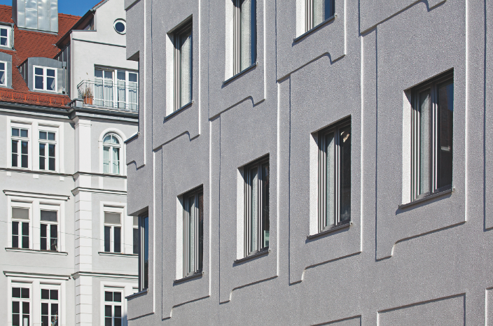 Büro- und Geschäftsgebäude Welfenstrasse, München, 2013: Das Relief der VAWD besteht aus Formelementen, deren Anordnung der regelmässigen Fensterstruktur folgt. Sie überlappen einander schuppenartig, sodass die Fassade nach oben hin um einige Zentimeter auskragt. Das Fassadenbild ist trotz seiner Flächigkeit reich gegliedert und gut proportioniert. Der warme Silberton des Silikonharz-Oberputzes veredelt die Fassade; sie wirkt elegant und wertig. Die dem Entwurf zugrunde liegenden Gesetzmässigkeiten