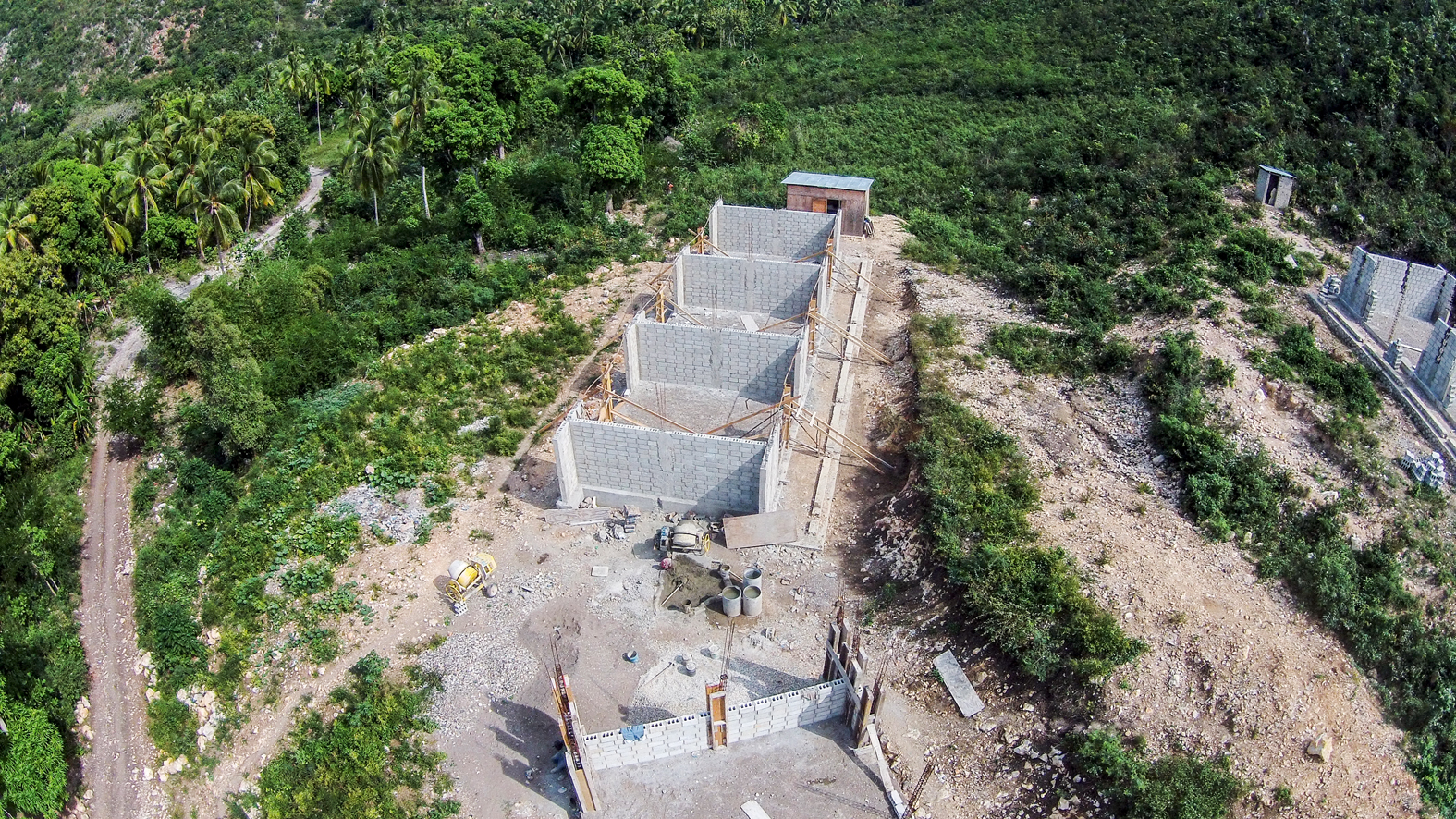 Typ «Eingefasstes Mauerwerk» im ländlichen Raum, ein eingeschossiger Massivbau mit Holzdach. Fünf solcher Schul­häuser sind fertiggestellt oder im Bau, wie hier die Ecole Nationale Lindor bei Miragoâne.