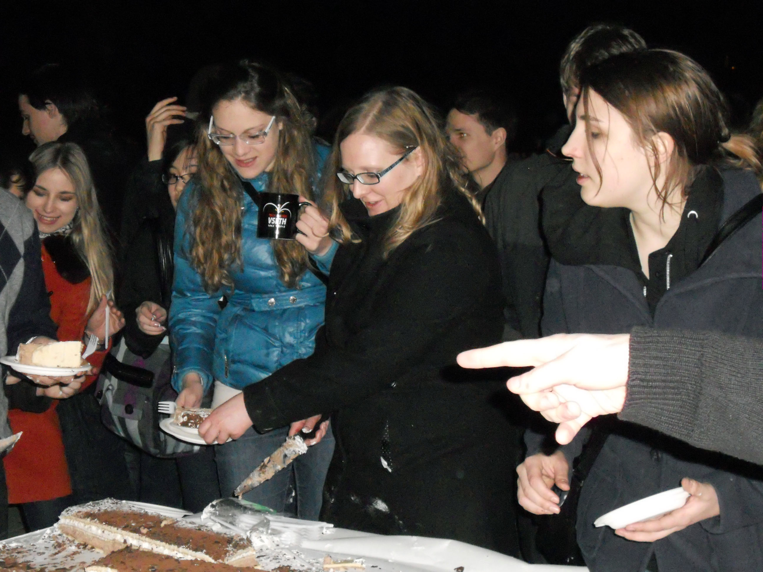 Die amtierende VSETH-Präsidentin, Rahel Zoller, verteilt Geburtstagskuchen. Im Bild auch eine der Jubiläumstassen, in die der Punsch ausgeschenkt wurde