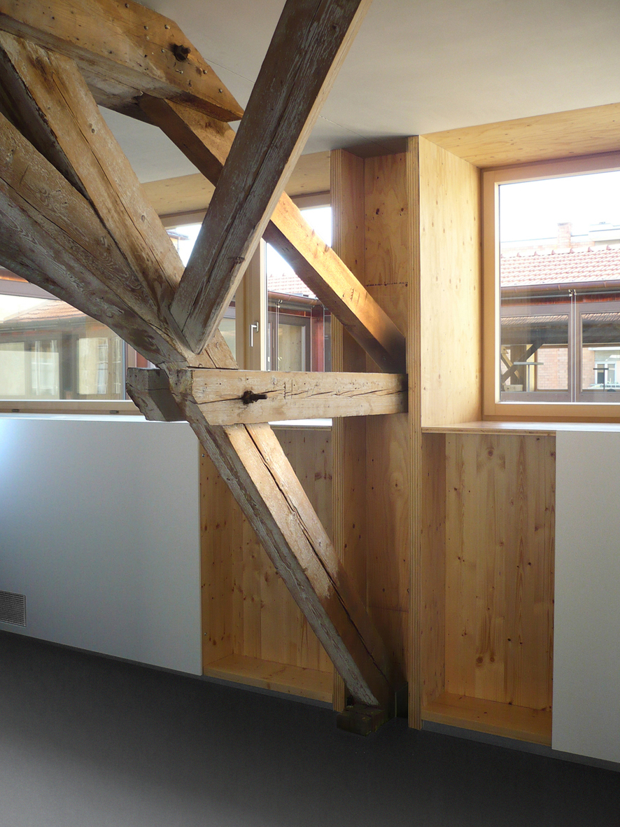 Die Tragstruktur des ehemaligen Verladeraums der Schokoladenfabrik Tobler in Lugano, ein Hetzerbinder der ersten Generation, wurde durch mit Pressklebung aufgebrachten, zusätzlichen Lamellen ertüchtigt. Tageslicht scheint durch die im Dach integrierten transluziden Bänder. Projekt: Jachen Könz, Lugano. Borlini &amp; Zanini Ingenieure, Lugano).