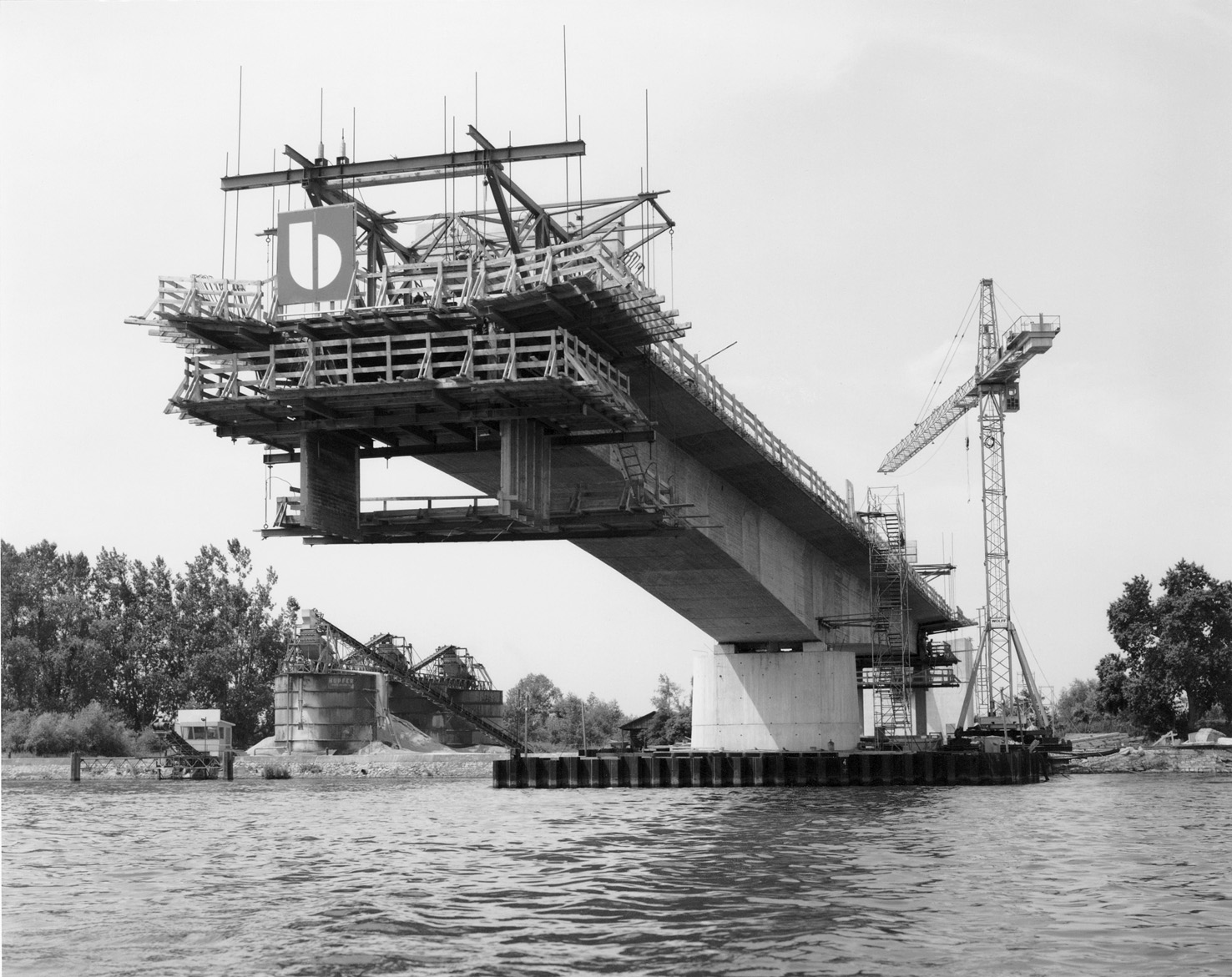 Freivorbauverfahren bei der Rheinbrücke am Palmrain 1979. Der Brückenträger wird vom Pfeiler aus nach beiden Seiten hin betoniert, ohne Abstützung des Gerüsts im Flussbett. )