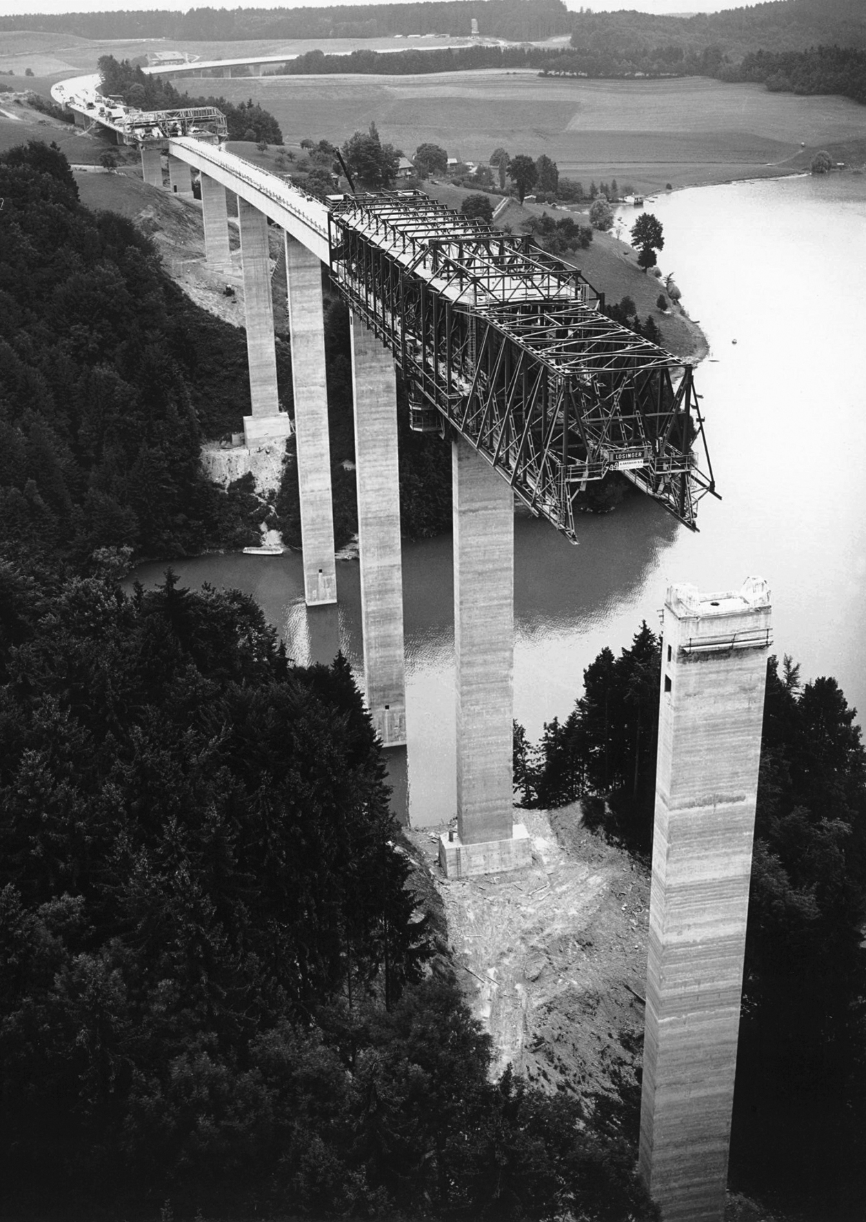 Viaduc du Lac de la Gruyère 1979. Im Vordergrund wird der Hohlkasten im Vorschubgerüst betoniert, im Hintergrund werden die Fahrbahnplatte und die Querrippen mit Nachlaufwagen erstellt.