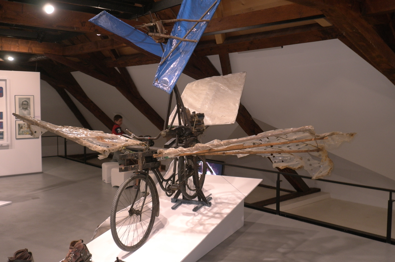 Ein Fluggerät von Gustav Mesmer, zusammengebaut aus einem Fahrrad, Latten und Plastikteilen in der Ausstellung in Lausanne. Im Vordergrund Sprungschuhe mit Federn, die Mesmer ebenfalls konstruiert hat. (Bild: Charles von Büren)
