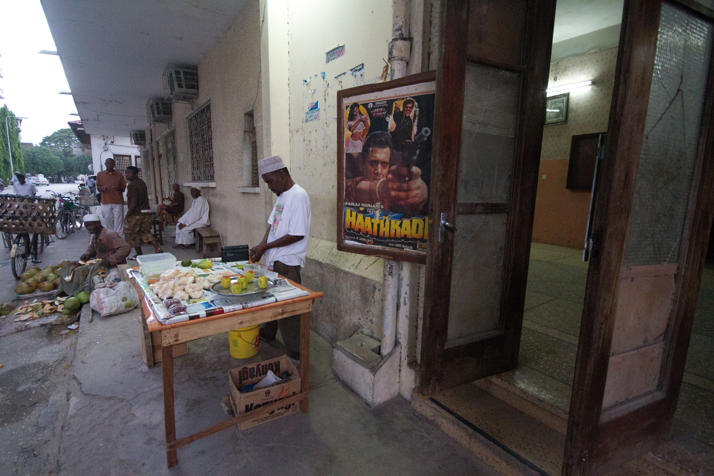 Des étals devant l’entrée du cinéma. Les locaux dans leur dos accueillent une librairie.