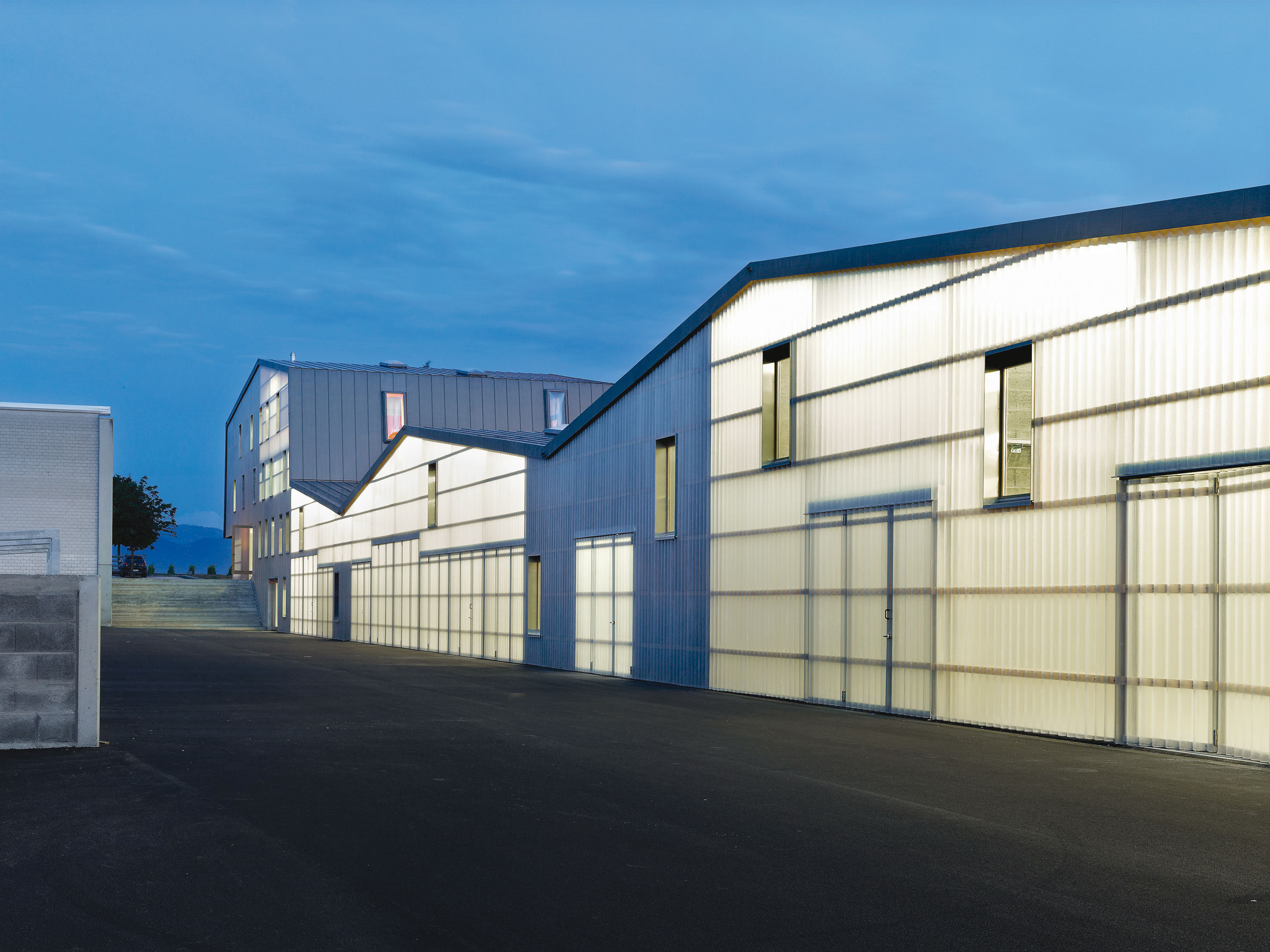 Vue de nuit du bâtiment des infrastructures, le jeu de lumière souligne le système constructif